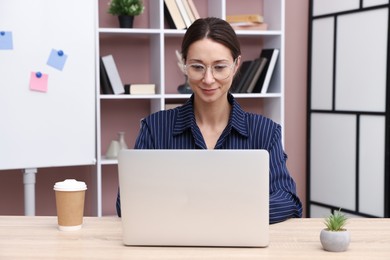 Photo of Online speaker streaming webinar with laptop at table indoors