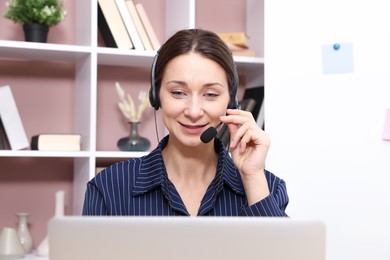 Photo of Smiling online speaker in headset streaming webinar with laptop indoors