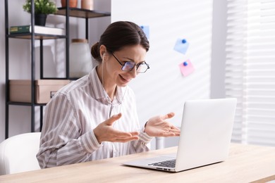 Photo of Smiling online speaker streaming webinar with laptop at table indoors