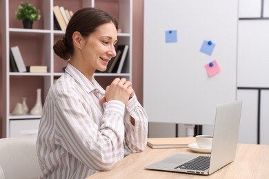 Photo of Smiling online speaker streaming webinar with laptop at table indoors