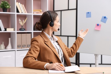 Photo of Online speaker in headset performing webinar near flip chart indoors