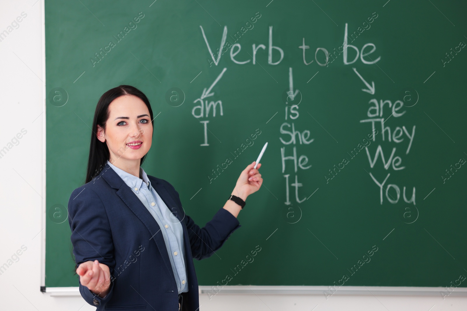 Photo of English teacher during lesson near chalkboard in classroom