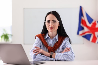 Photo of English teacher working on laptop at desk in classroom