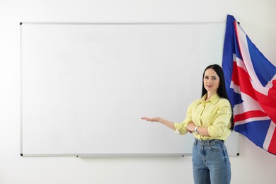 Photo of English teacher explaining something near whiteboard in classroom. Space for text