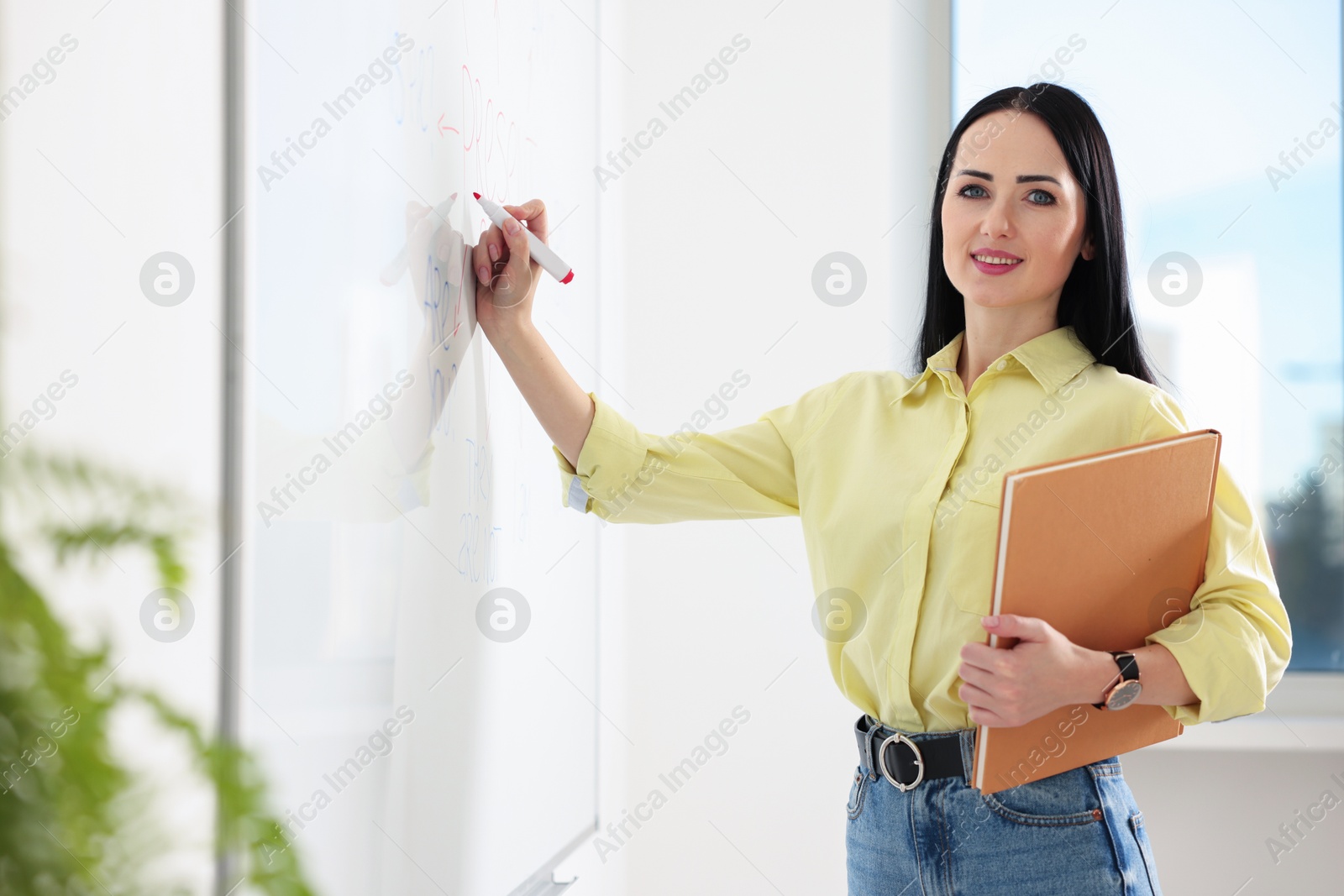 Photo of English teacher writing on whiteboard in classroom