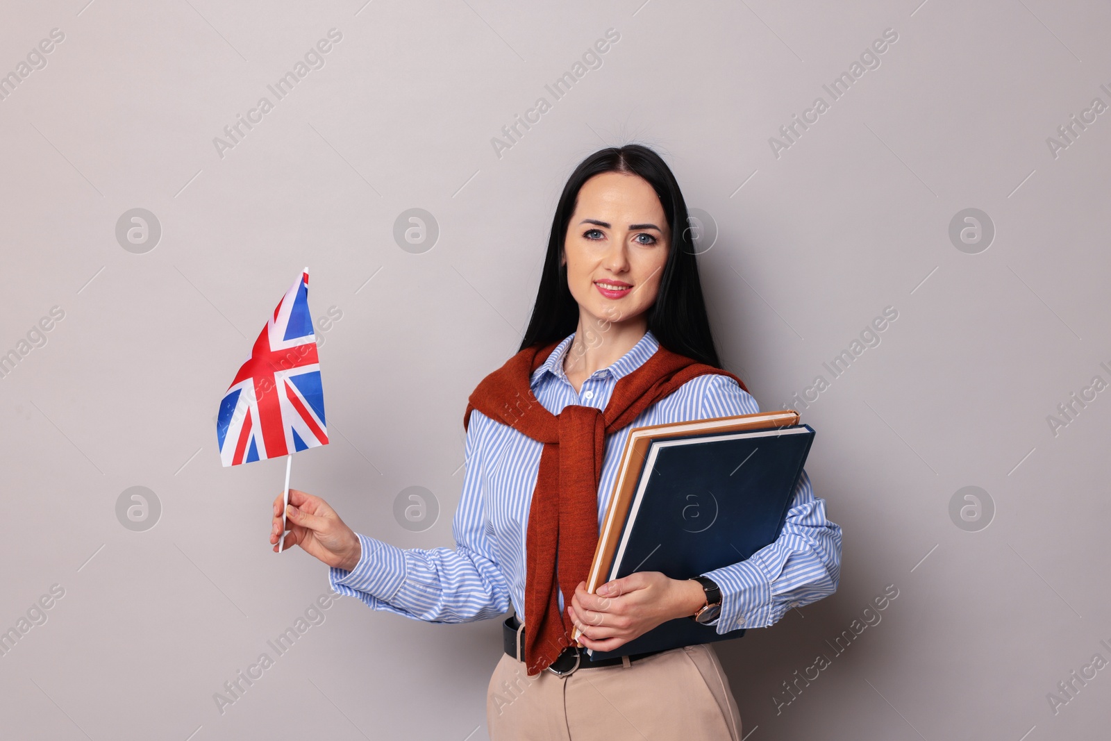 Photo of English teacher with books and UK flag on light grey background