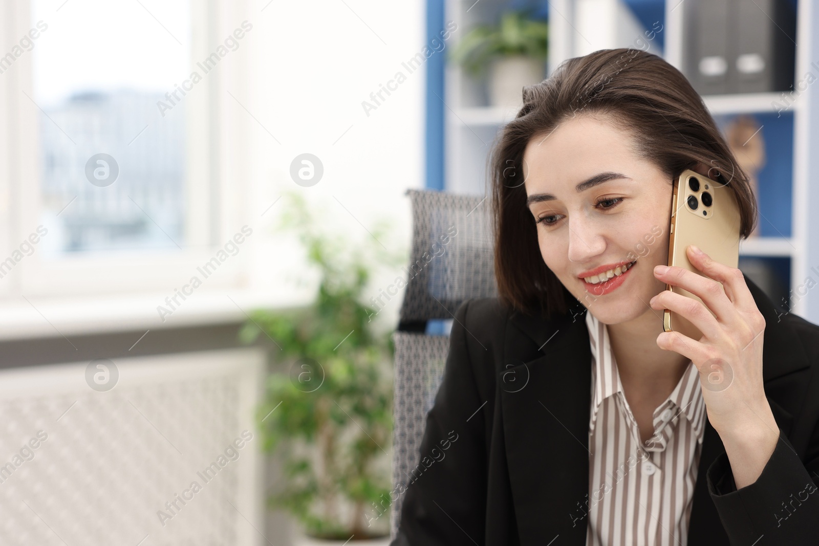 Photo of Smiling secretary talking on smartphone in office. Space for text