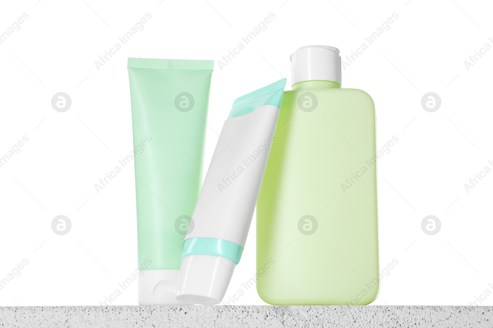 Different sun protection products on concrete surface against white background Photo of Different sun protection products on concrete surface against white background