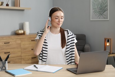 Photo of Woman learning online using laptop at table indoors. Self-study