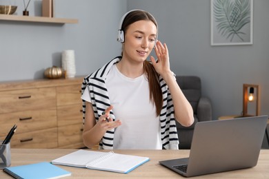 Photo of Smiling woman having online lesson with teacher by laptop at table indoors