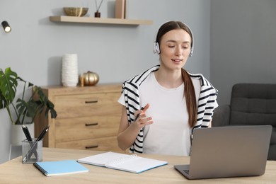 Photo of Smiling woman having online lesson with teacher by laptop at table indoors