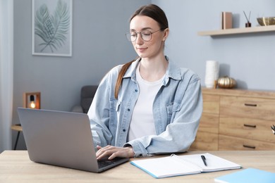 Photo of Woman learning online using laptop at table indoors. Self-study