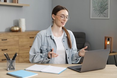 Photo of Smiling woman having online lesson with teacher by laptop at table indoors