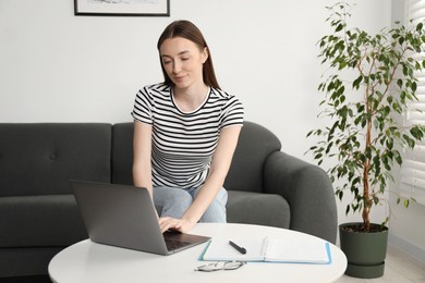 Photo of Woman learning online using laptop at table indoors. Self-study