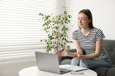 Photo of Smiling woman having online lesson with teacher by laptop at table indoors. Space for text