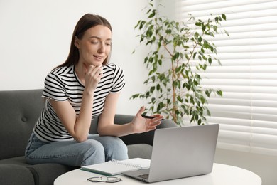 Photo of Smiling woman having online lesson with teacher by laptop at table indoors