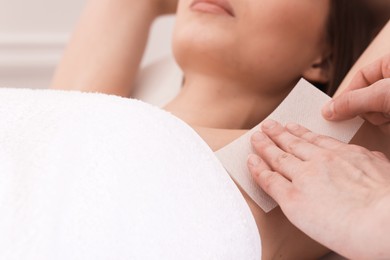 Photo of Woman undergoing wax epilation procedure in beauty salon, closeup