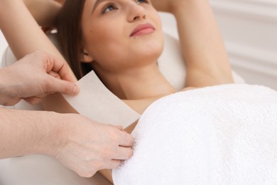 Photo of Woman undergoing wax epilation procedure in beauty salon, selective focus