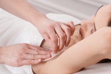 Photo of Woman undergoing wax epilation procedure in beauty salon, closeup