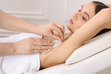 Photo of Woman undergoing wax epilation procedure in beauty salon