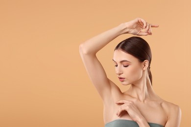 Photo of Young woman showing smooth skin after epilation on beige background, space for text