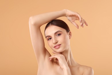 Photo of Young woman showing smooth skin after epilation on beige background