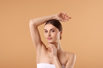 Photo of Young woman showing smooth skin after epilation on beige background