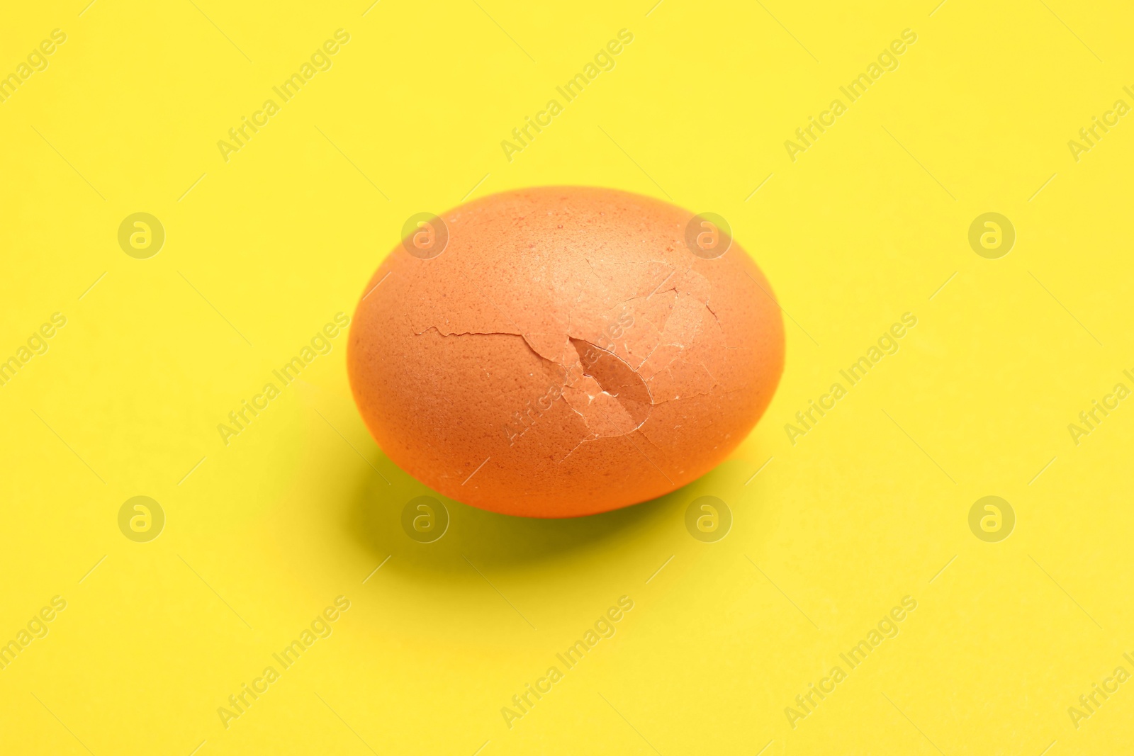 One egg with cracked shell on yellow background Photo of One egg with cracked shell on yellow background