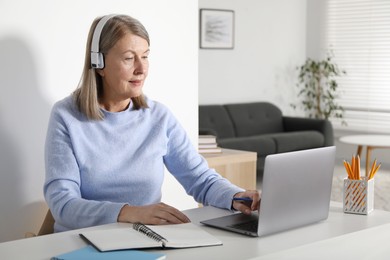 Photo of Woman learning online using laptop at table indoors. Self-study