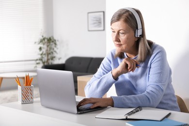 Photo of Woman learning online using laptop at table indoors. Self-study