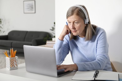 Photo of Woman learning online using laptop at table indoors. Self-study