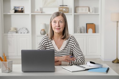 Photo of Woman learning online using laptop at table indoors. Self-study