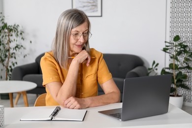 Photo of Woman learning online using laptop at table indoors. Self-study