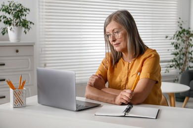 Photo of Woman learning online using laptop at table indoors. Self-study