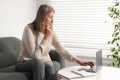 Photo of Woman learning online using laptop at table indoors. Self-study