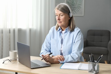 Photo of Woman learning online using laptop at table indoors. Self-study