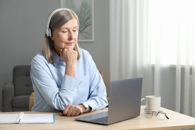 Photo of Woman learning online using laptop at table indoors. Self-study