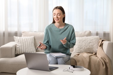 Photo of Smiling woman having online lesson with teacher by laptop at table indoors