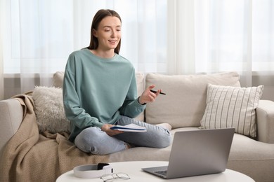 Photo of Smiling woman having online lesson with teacher by laptop at table on sofa indoors