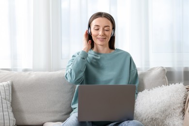 Photo of Smiling woman learning online using laptop on sofa indoors. Self-study