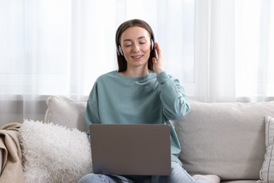 Photo of Smiling woman learning online using laptop on sofa indoors. Self-study