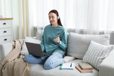 Photo of Smiling woman having online lesson with teacher by laptop on sofa indoors