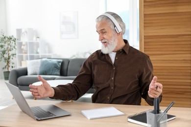 Photo of Senior man having online lesson with teacher at desk indoors. Self-study