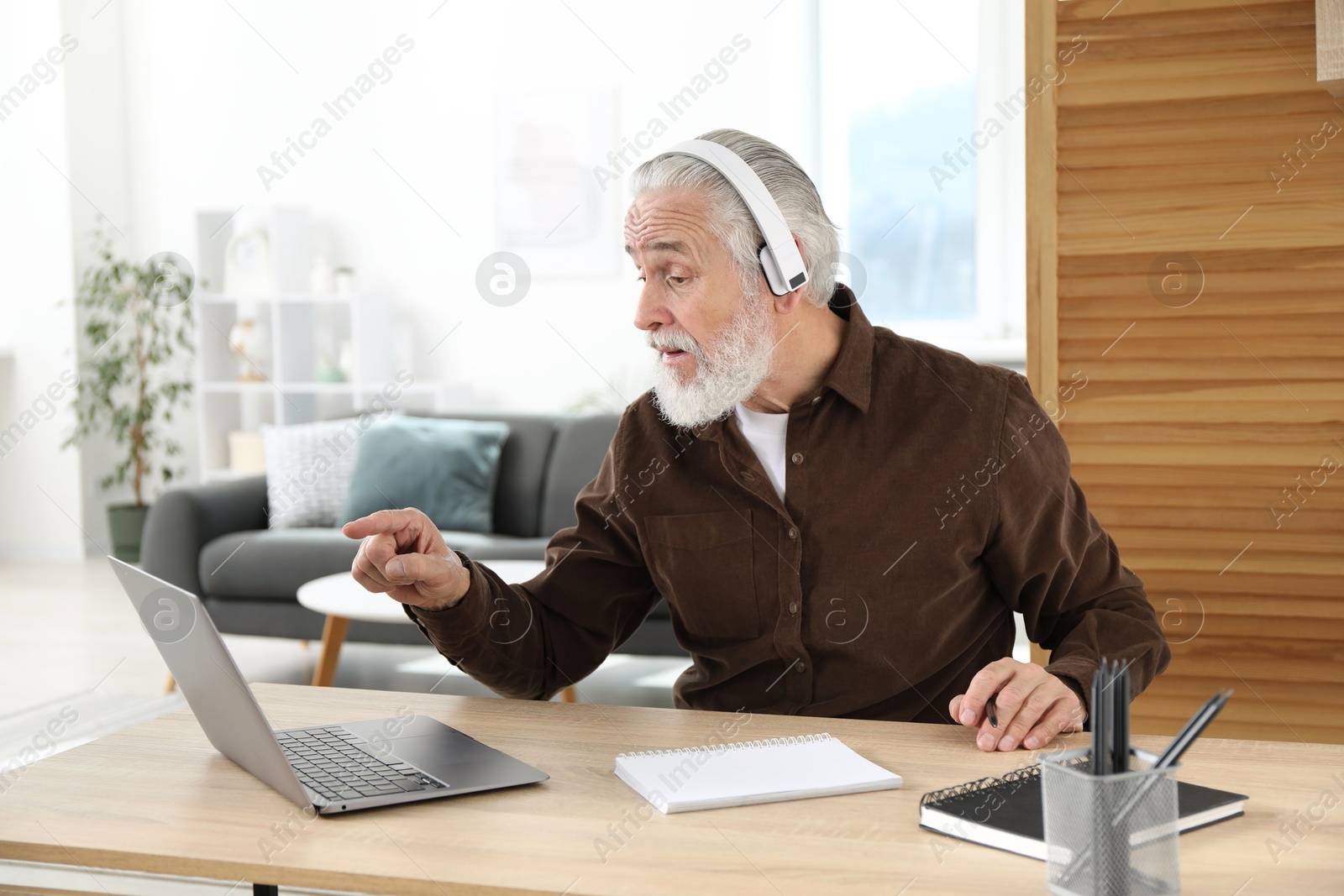 Photo of Senior man having online lesson with teacher at desk indoors. Self-study