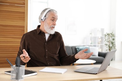 Photo of Senior man having online lesson with teacher at desk indoors. Self-study