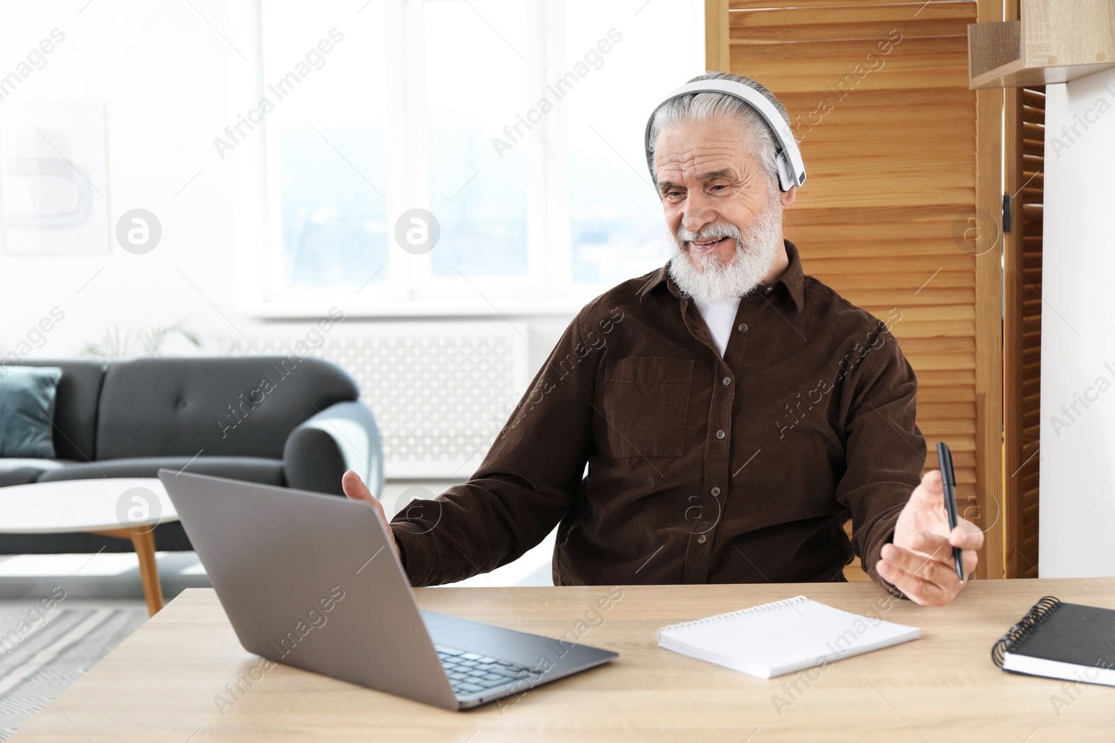 Photo of Senior man learning online using laptop at desk indoors. Self-study