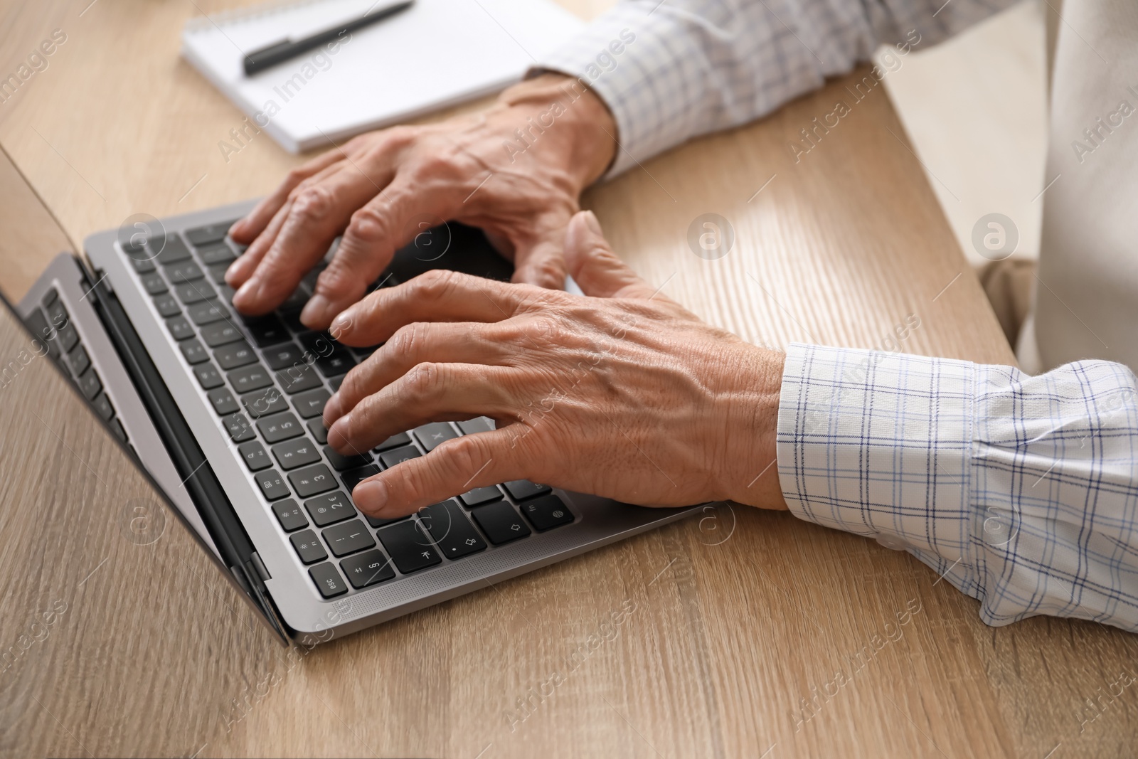 Photo of Senior man learning online using laptop at desk indoors, closeup. Self-study