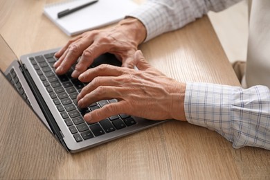 Photo of Senior man learning online using laptop at desk indoors, closeup. Self-study