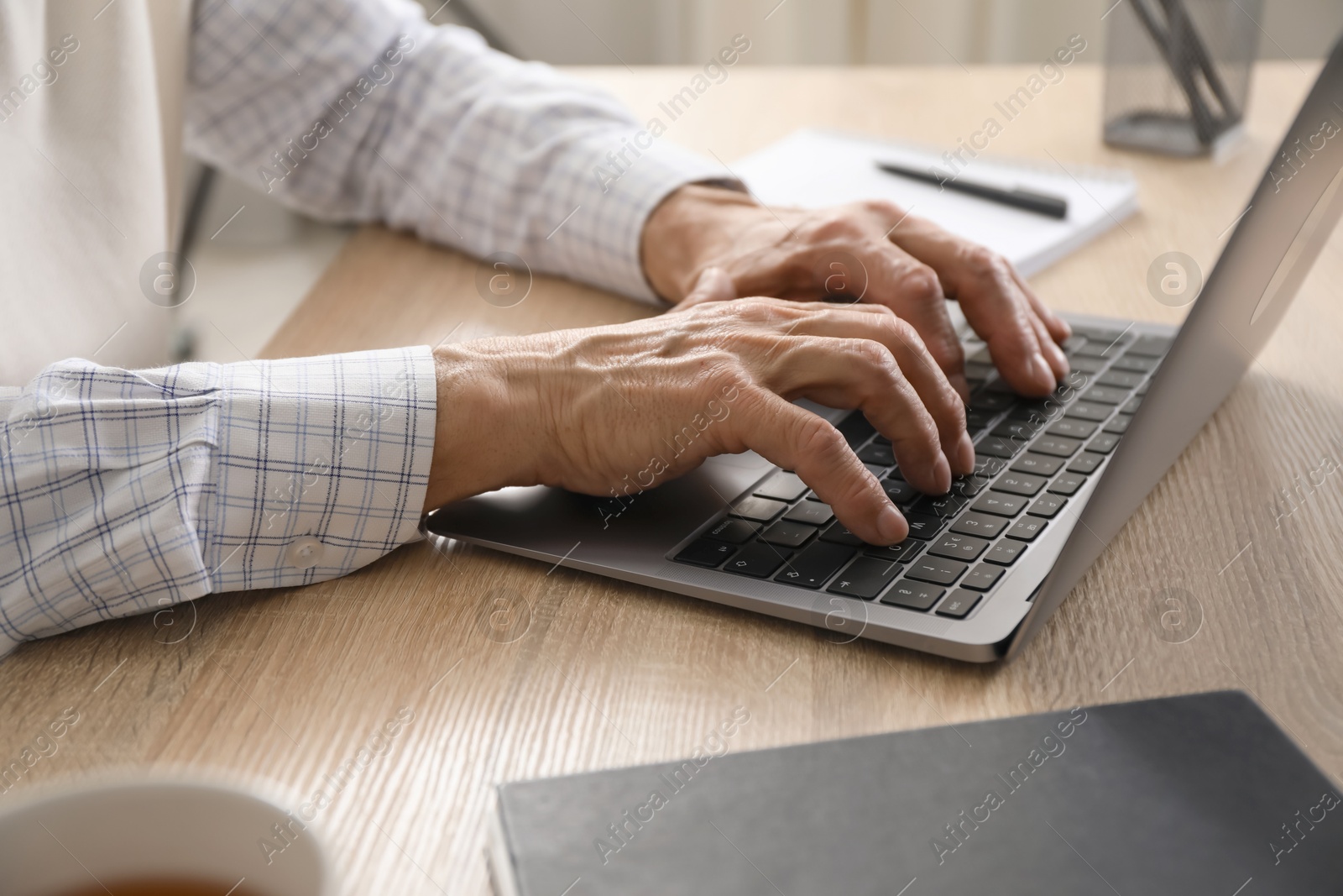 Photo of Senior man learning online using laptop at desk indoors, closeup. Self-study