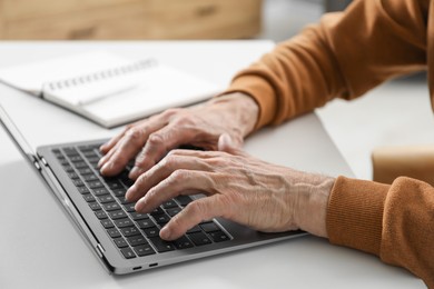 Photo of Senior man learning online using laptop at desk indoors, closeup. Self-study